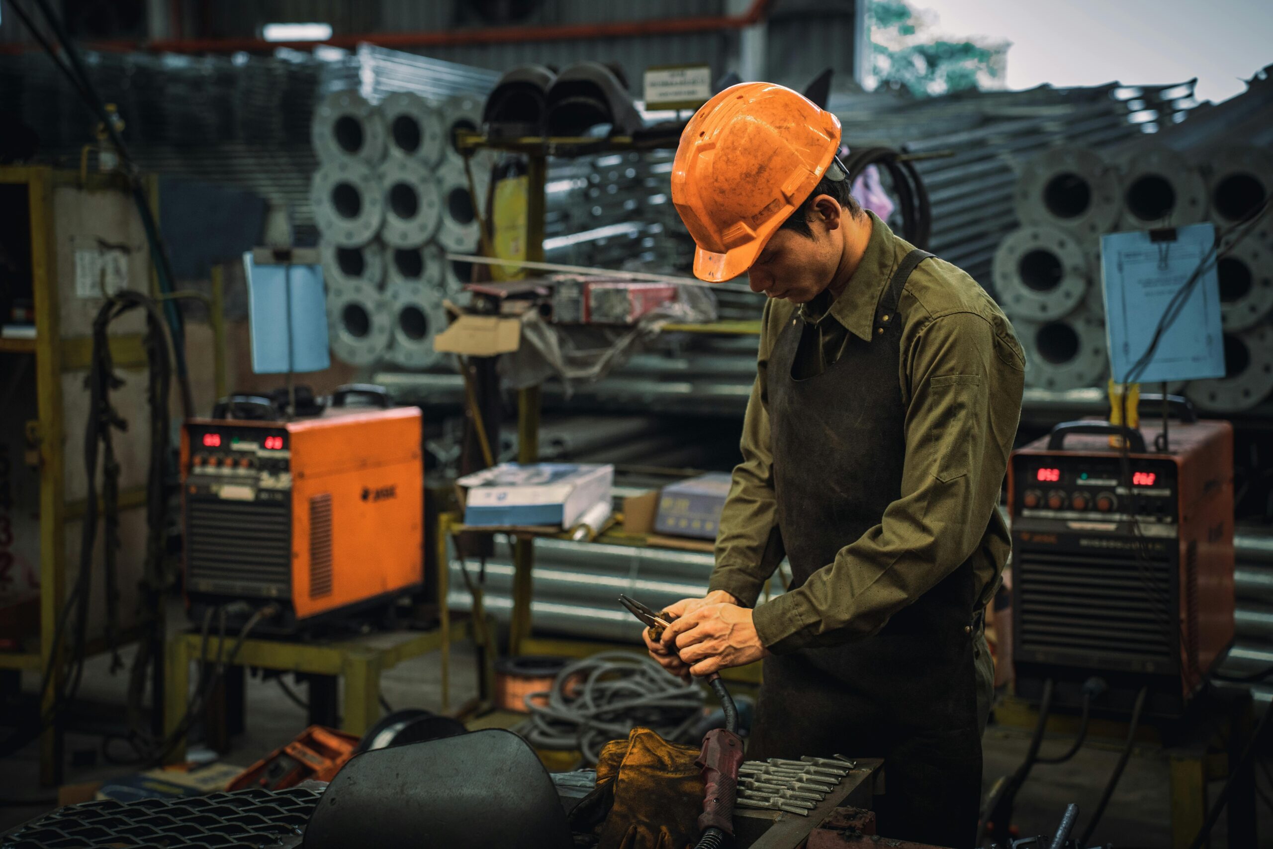 A factory worker wearing safety gear operating machinery in an industrial setting.