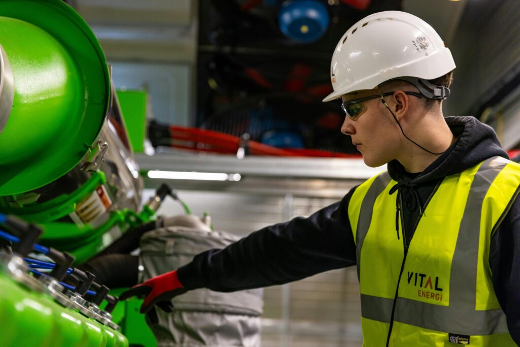 Safety-focused worker operating machinery indoors, wearing protective gear.